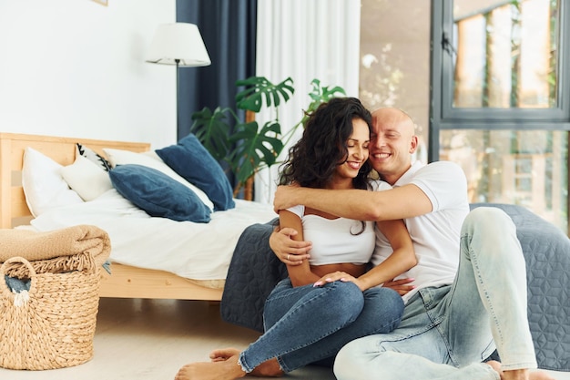 Assis et s'embrassant Un couple joyeux est ensemble à l'intérieur