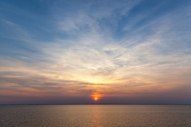 Assis le soleil contre le ciel. Le ciel est au coucher du soleil.