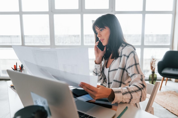 Assis à table Jeune travailleuse indépendante est à l'intérieur de la maison pendant la journée