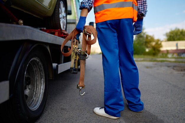 Assistant de dépanneuse mâle tenant des ceintures pour la fixation de la voiture pour le transport en toute sécurité. Photo en gros plan