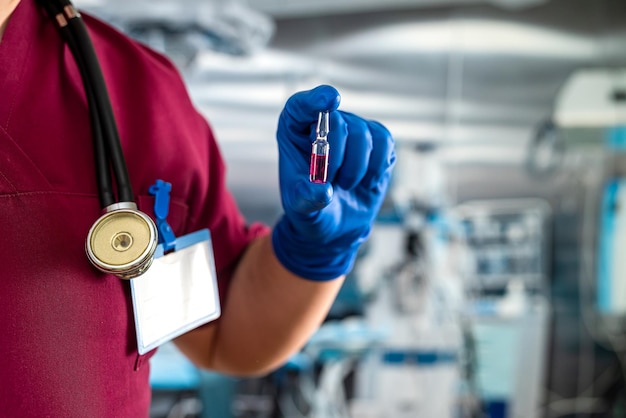 Assistant médical main dans les gants tenant une bouteille de flacon de vaccin ou d'anesthésie dans le cabinet chirurgical de l'hôpital