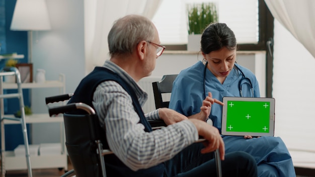Assistant médical tenant une tablette avec écran vert horizontal