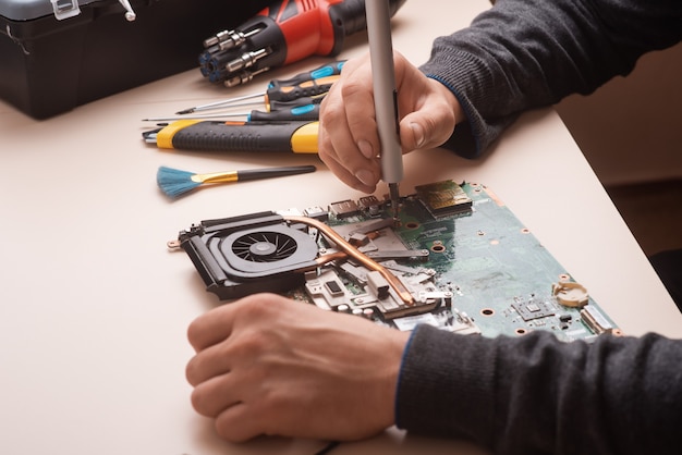 L'assistant restaure l'ordinateur portable. Démontage de l'ordinateur portable en pièces détachées. Conseil, partie de l'ordinateur portable pour la récupération. Maintenance du matériel informatique à l'aide d'outils. Vue de l'ordinateur portable à l'intérieur