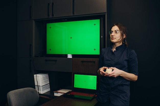 Assistant utilisant un écran vert horizontal sur ordinateur pendant que le dentiste prépare l'équipement pour l'examen de soins bucco-dentaires dans le cabinet dentaire Homme regardant la clé chroma et le modèle de maquette sur le moniteur