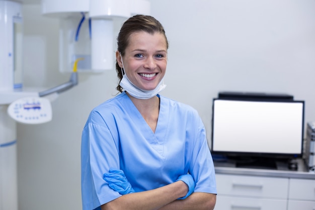 Photo assistante dentaire souriante debout avec les bras croisés