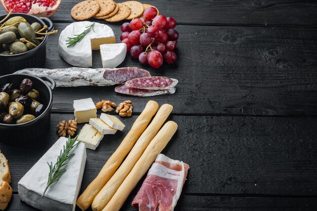 Assortiment d'apéritifs au fromage et à la viande, sur une table en bois noir avec espace de copie pour le texte