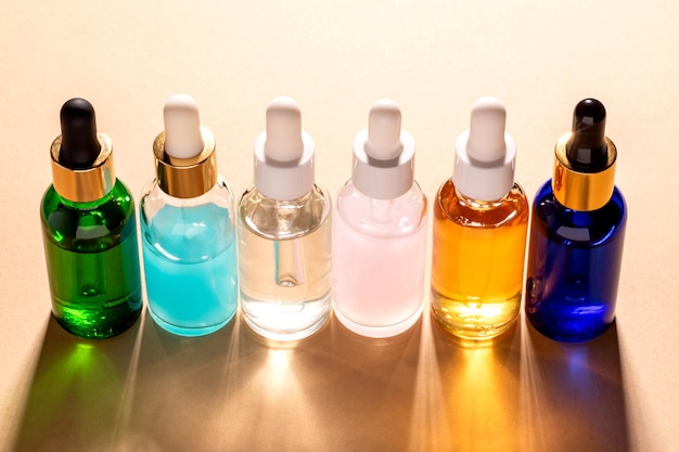 Photo assortiment de bouteilles goutte-à-goutte avec sérum pour le visage ou huile de beauté sur fond beige présentation de concepts de soins de la peau et de cosmétiques