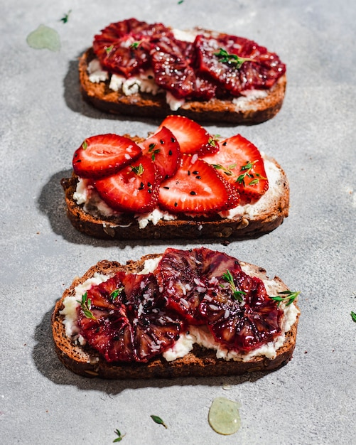 Assortiment de bruschetta avec pain de grains entiers, fromage cottage, orange sanguine, fraise, thym