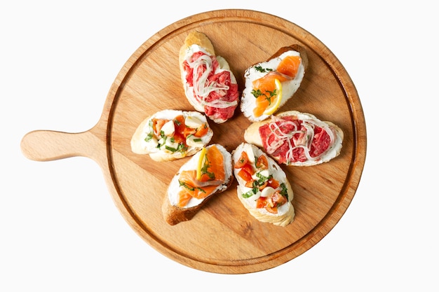 Assortiment de bruschettas sur une planche de bois. Collation Areret. Vue de dessus. Isolé sur blanc.