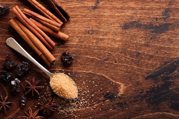 Assortiment de cannelle naturelle, sucre brun de canne, café moulu, étoiles d'anis ingrédients de cuisson sur une table brune rustique.