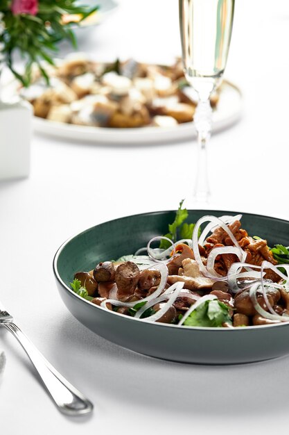 Assortiment de champignons salés, sur une assiette sur une table décorée de façon festive avec des nappes blanches, un mélange de champignons lance.