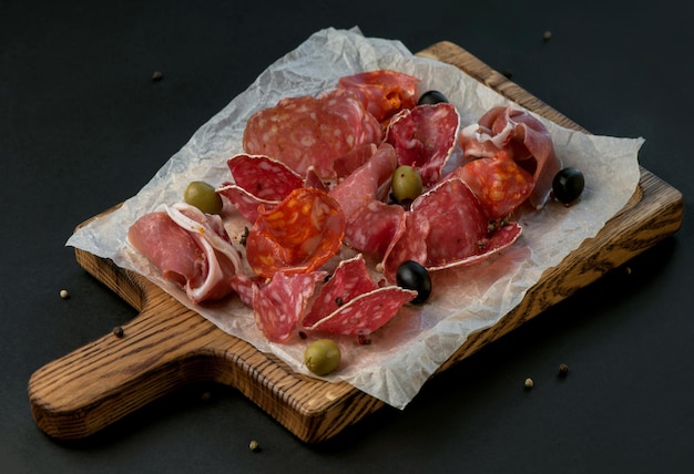 Assortiment de charcuterie espagnole. Chorizo, fuet, LOMO, jambon ibérique, olives. Fond noir. Vue de dessus.