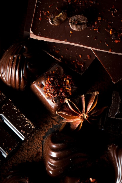 Assortiment de chocolat noir, blanc et au lait sur fond sablant en bois rustique.