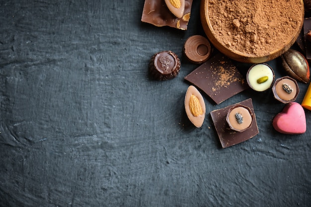 Assortiment de chocolat et de poudre de cacao sur fond noir