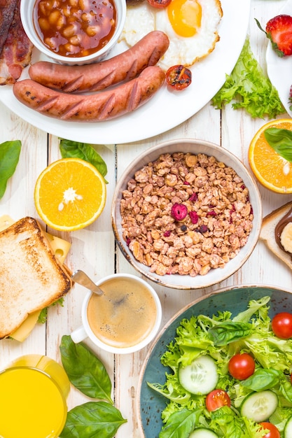 Assortiment de choix de petit-déjeuner. Petit-déjeuner anglais, saucisses, œufs au plat, bacon, salade, granola