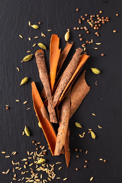 Assortiment de concepts alimentaires Cosses de cardamome, graines de coriandre, fenouil et bâtons de cassia à l&#39;écorce de cannelle sur ardoise noire