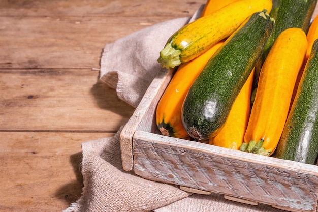 Assortiment de courgettes fraîches. Récolte de légumes mûrs dans une boîte en bois. Table de planches vintage, espace de copie