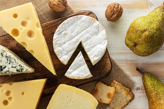 Assortiment de différents types de fromages sur table en bois blanc.