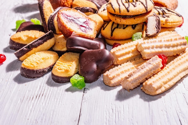 Assortiment de divers biscuits et cupcakes. Lumière dure à la mode, ombre sombre. Fond de planches de bois blanc, espace de copie