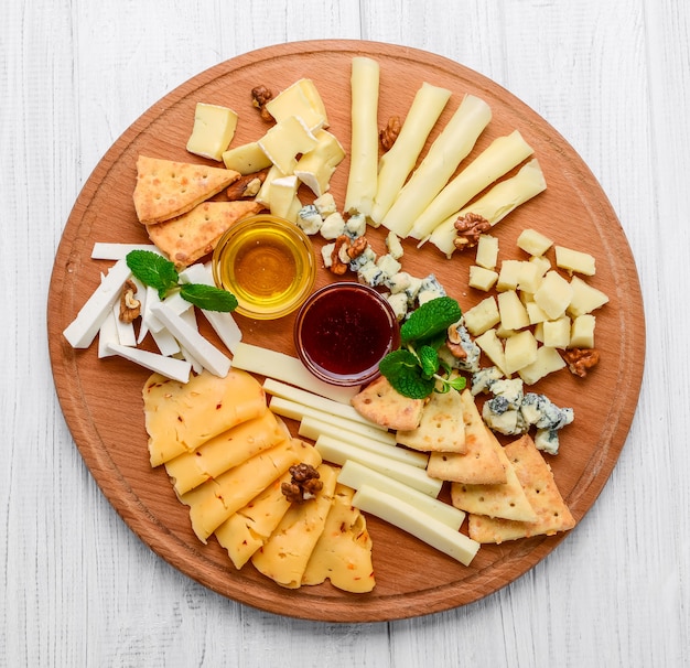 Assortiment de fromages sur ardoise noire, noix et miel, décoré de raisins et de feuilles de menthe