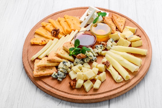 Assortiment de fromages sur ardoise noire, noix et miel, décoré de raisins et de feuilles de menthe