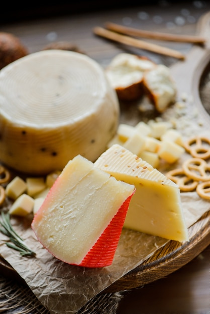 Assortiment de fromages à pâte dure avec bretzels sur la planche à découper. Sur un fond en bois. Mise au point sélective.