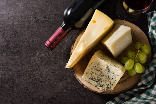 Assortiment de fromages et de vin sur fond noir.