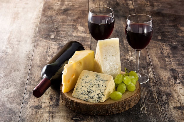 Assortiment de fromages et de vin sur une table en bois.