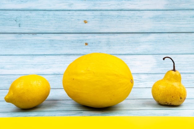 Photo un assortiment de fruits jaunes se trouve sur un fond en bois bleu et un fond jaune