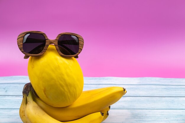 Photo un assortiment de fruits jaunes et de verres se trouve sur un fond rose