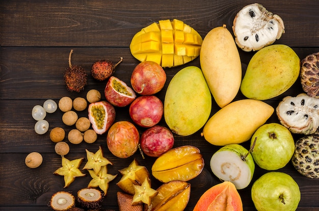 Assortiment de fruits tropicaux thaïlandais sur un fond rustique en bois foncé.