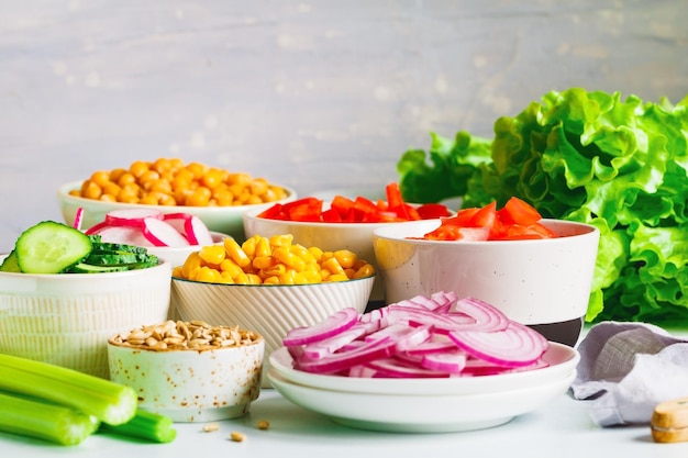 Assortiment d'ingrédients pour une salade végétarienne saine dans différents bols de portion sur une table Le concept de remise en forme et de nourriture végétalienne