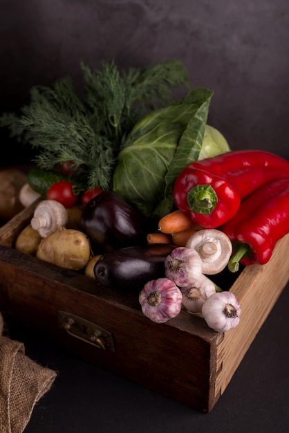 Assortiment de légumes crus frais dans une boîte en bois sur fond noir Aliments locaux biologiques sains