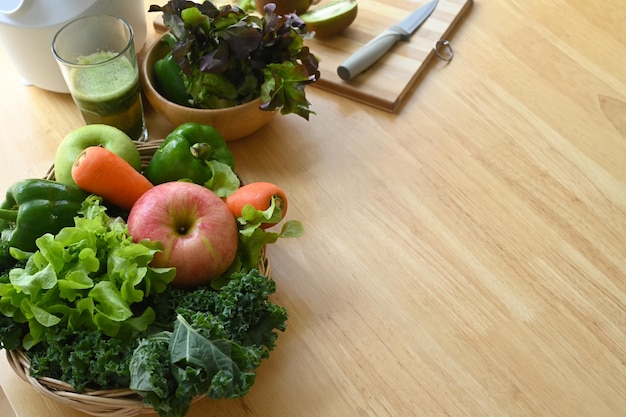 Assortiment de légumes et de fruits biologiques dans un panier en osier sur une table en bois