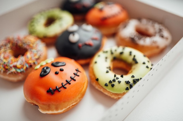 Assortiment de monstres d'halloween avec des beignets de grimaces dans une boîte à l'intérieur de la maison