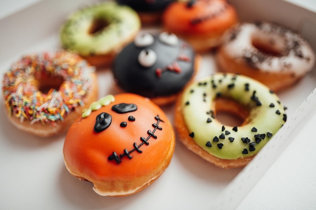 Assortiment de monstres d'Halloween avec des visages drôles des beignets dans la boîte à l'intérieur de la maison