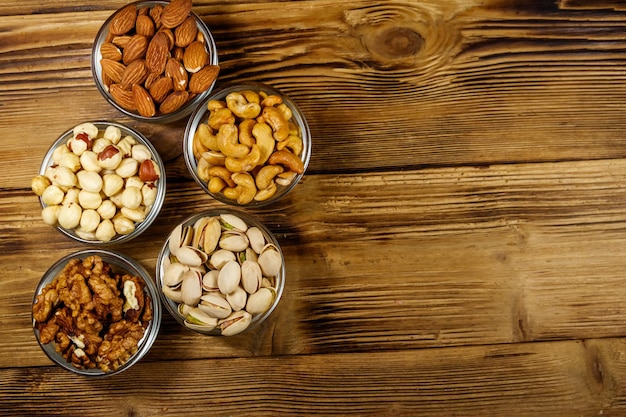 Assortiment de noix sur table en bois Amande noisette pistache noix et noix de cajou dans des bols en verre Vue de dessus espace de copie Concept de saine alimentation