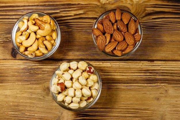Assortiment de noix sur table en bois Noisette d'amande et noix de cajou dans des bols en verre Vue de dessus Concept de saine alimentation