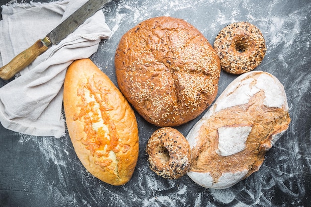 Assortiment de pain et petits pains frais sur fond noir, vue de dessus