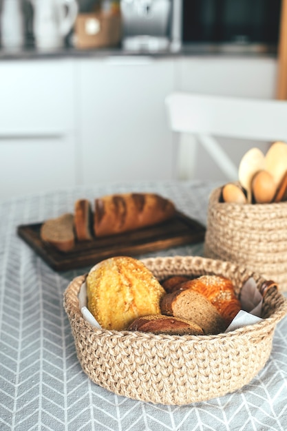 Assortiment de pain sans gluten, pain de maïs et de seigle dans un panier artisanal en jute sur la table de la cuisine