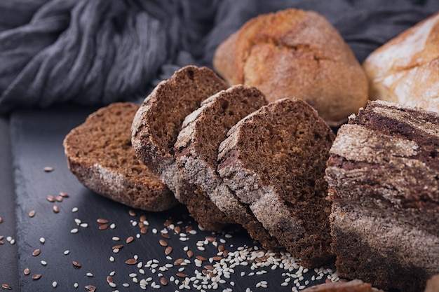 Assortiment de pains cuits au four sur fond sombre. Pain de seigle tranché. Concept de magasin d'alimentation de boulangerie et d'épicerie.