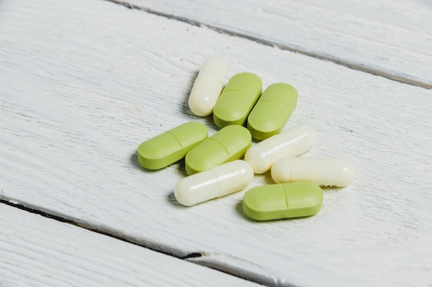 Assortiment de pilules, comprimés et capsules sur une table en bois.