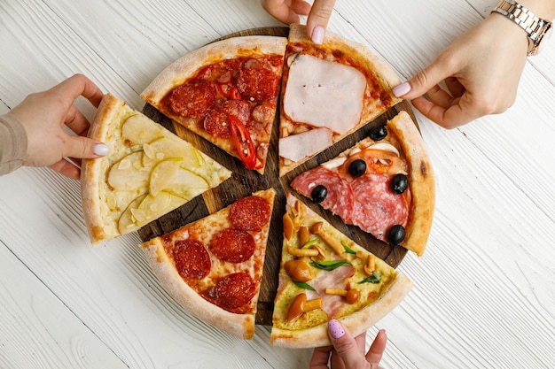 Assortiment de pizzas italiennes sur une table en bois blanche Différentes pièces dans un ensemble de portions