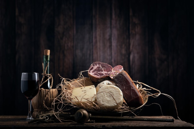 Assortiment de salumi au fromage fait maison sur une table en bois avec un fond en bois Gros plan