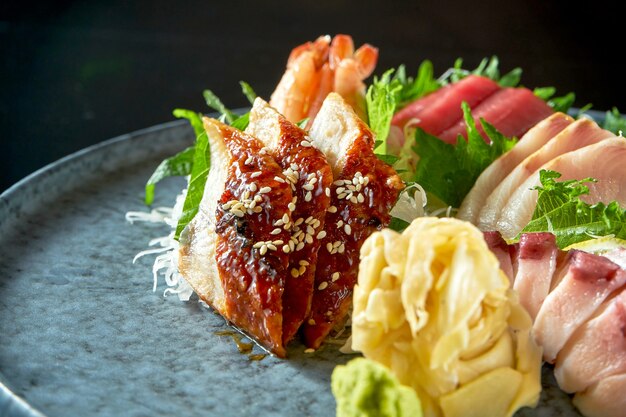 Assortiment de sashimi de saumon, crevette, thon, poulpe, pétoncle et anguille. Cuisine japonaise classique. Livraison de nourriture. Isolé sur fond noir