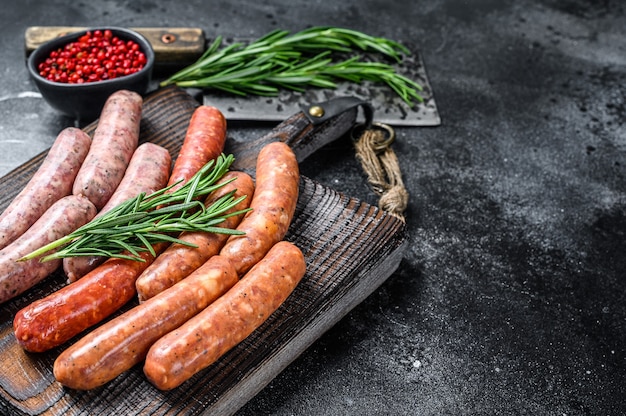 Assortiment de saucisses chorizo crues sur une planche à découper en bois.