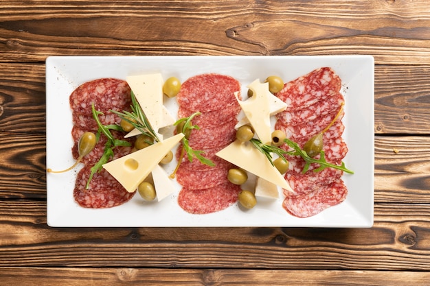 Assortiment de saucisses de salami tranchées finement avec fromage, olives, câpres et roquette