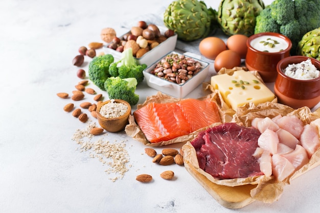 Assortiment de sources de protéines saines et d'aliments de musculation Viande boeuf saumon poitrine de poulet oeufs produits laitiers fromage yaourt haricots artichauts brocoli noix farine d'avoine Copier l'arrière-plan de l'espace