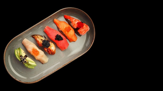 Photo assortiment de sushis nigiri sur une assiette sur du béton foncé vue de dessus