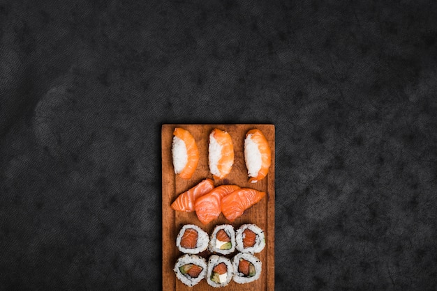 Assortiment de sushis sur un plateau en bois sur fond de texture noire
